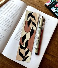 an open book on a wooden table next to a pen