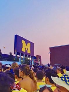 a large group of people standing in front of a building with a sign that says michigan