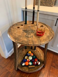 a wooden table with pool balls on it in a room next to a basket filled with candles