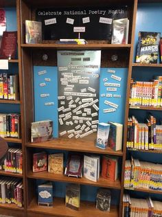 a bookshelf filled with lots of books next to a wall covered in posters