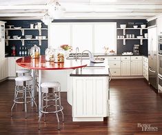 a kitchen with white cabinets and an island in the middle, surrounded by bar stools