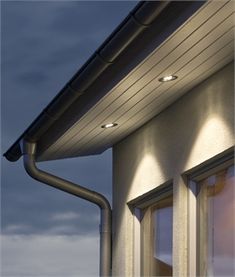 two lights are shining on the side of a building with windows and gutter pipes