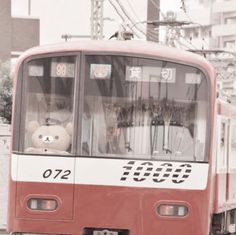 a red and white train traveling down tracks next to tall buildings