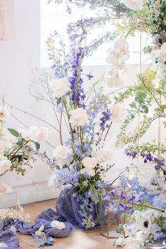 a vase filled with lots of white and blue flowers on top of a wooden floor