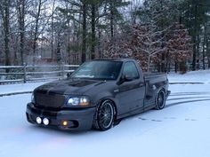 a black truck parked in the snow next to trees