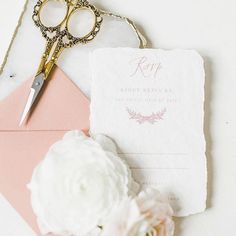 a pair of scissors sitting on top of a piece of paper next to a flower