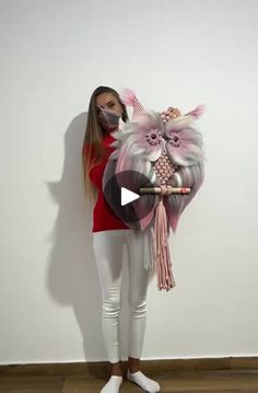 a woman standing in front of a white wall with an owl mask on her face