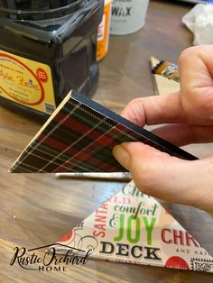 someone is holding a small piece of paper in front of some other items on the table