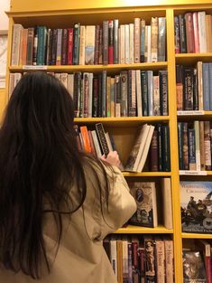 a woman standing in front of a book shelf filled with books