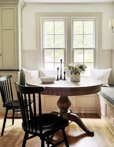 a kitchen table with two chairs and a bench in front of the window, next to a breakfast nook