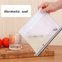 a person pouring water into a glass on top of a cutting board next to tomatoes