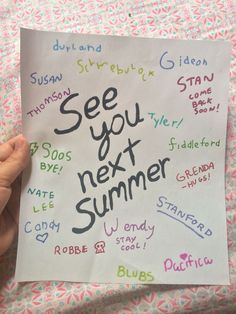 someone holding up a sign that says see you next summer written in different languages on it