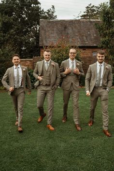 three men in suits and ties are standing on the grass with their hands behind their backs