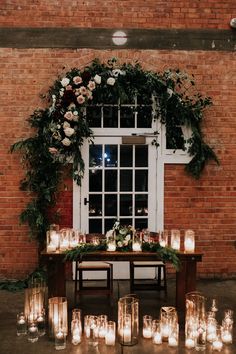 a table with candles and flowers on it in front of a window filled with greenery