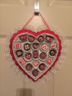 a heart shaped decoration hanging on the wall in front of a door with lace doily