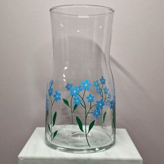 a glass vase with blue flowers painted on it