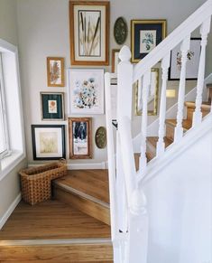 a staircase with pictures on the wall above it and a wicker basket under the banister