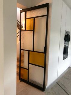 an open door in the middle of a room with white walls and yellow glass panels