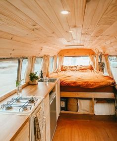 the interior of a small camper with wood flooring and white walls, including a bed