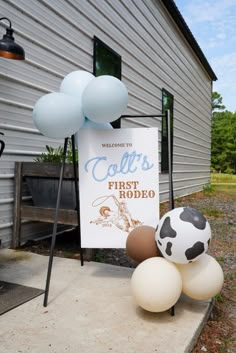 some balloons and a sign on the side of a house that says colt's first rodeo