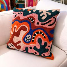 a colorful pillow on a white couch in a room