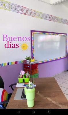 a classroom with a large whiteboard and colorful decorations on the wall, along with two desks