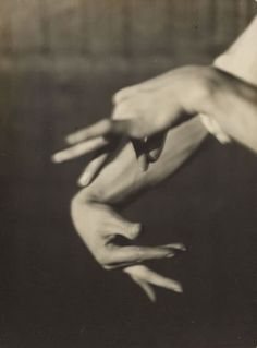 two hands reaching towards each other with their fingers extended out to touch the ground, in black and white