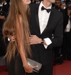 a man and woman standing next to each other in front of photographers on the red carpet