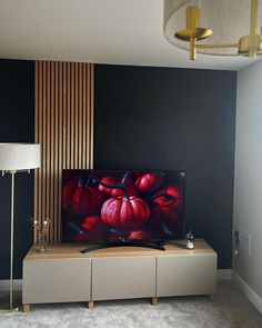 a flat screen tv sitting on top of a wooden entertainment center next to a lamp