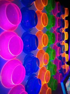 neon colored plastic cups are lined up on the wall