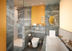 a bathroom with marble walls and flooring in yellow, grey and white colors is shown