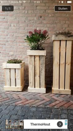 two wooden planters sitting next to each other on a brick floor in front of a wall