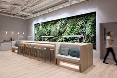 the interior of an office with lots of seating and plants on the wall behind it