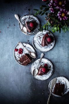 three desserts with chocolate cake and raspberries on them, one is half eaten