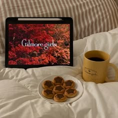 a plate of cookies next to a cup of coffee on a bed with a laptop