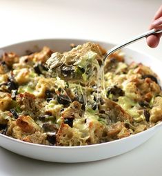 a casserole dish with broccoli, mushrooms and cheese being drizzled over it