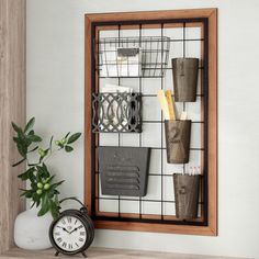 a clock and some plants on a shelf next to a wall mounted rack with wire baskets