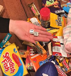 a person's hand with dices on top of candy and other items in front of them