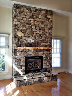 a living room with a stone fireplace and hard wood floors