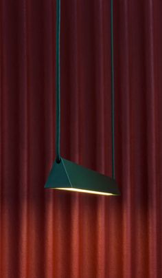 a lamp hanging from the ceiling in front of a red curtain