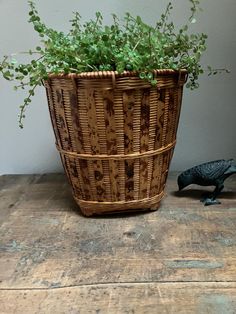 a toy bird next to a basket with plants in it