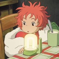 a young boy sitting at a table with a light in front of him and a mug on the table