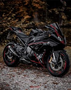 a black motorcycle parked on top of a gravel road next to trees and bushes in the background