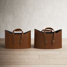 two brown leather bags sitting next to each other on top of a hard wood floor