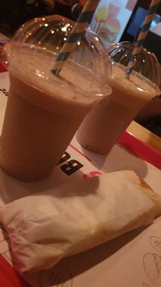 two drinks in plastic cups sitting on top of a table