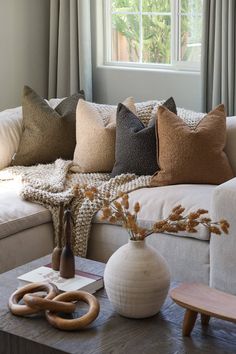 a living room filled with lots of pillows on top of a white couch next to a window