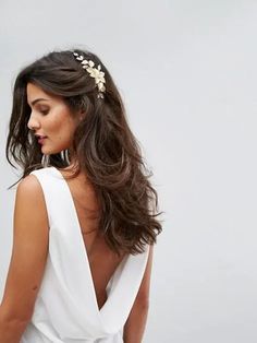 a woman wearing a white dress with a flower headpiece in her hair and looking off to the side