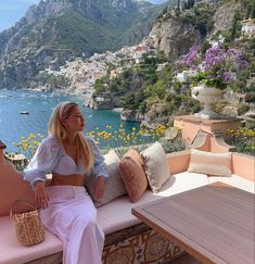 a woman sitting on top of a bench next to a table with flowers in it