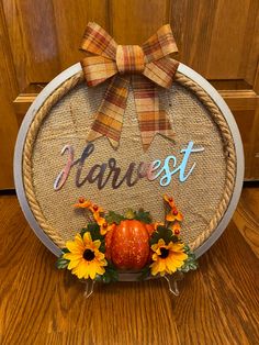 a wooden sign that says harvest with sunflowers and an orange pumpkin on it