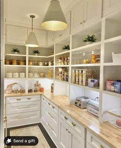 a kitchen filled with lots of white cupboards and counter top space next to a light fixture